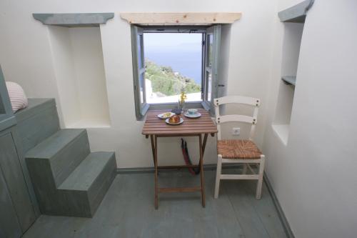 EmporeiósPyrgos Stone House的窗户客房内的小桌子和椅子
