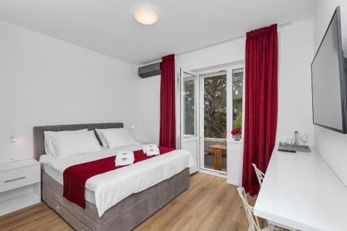 马卡尔斯卡Luxury Rooms Paradise Garden的一间卧室配有一张带红色窗帘的大床