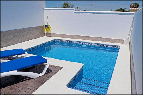 科尼尔-德拉弗龙特拉Casa Rural Zara II的一个带椅子和桌子的游泳池以及一个蓝色的泳池景