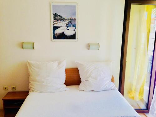 卡什泰拉Apartments Ruza的一张带白色枕头的床和一张墙上的照片