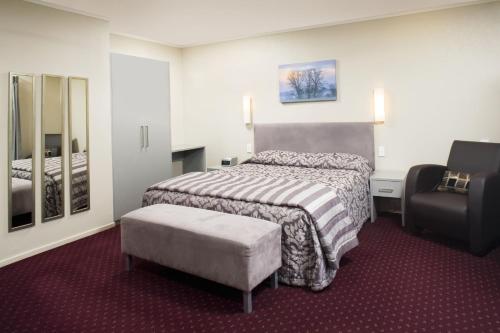 奥克兰曼努考汽车旅馆的配有一张床和一把椅子的酒店客房