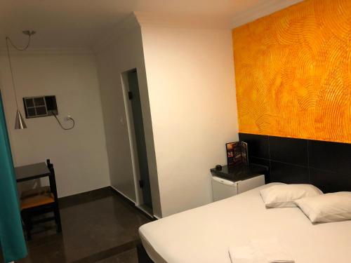 圣保罗Hotel Romance (Adults Only)的卧室配有白色的床和墙上的绘画作品