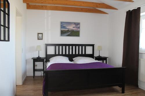 旺格兰兹姆滕克鲁格旅馆的一间卧室配有一张黑色床、紫色床单和白色枕头