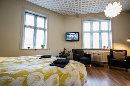 霍尔斯特布罗Bed & Breakfast Holstebro的一间卧室配有一张床、两把椅子和一台电视