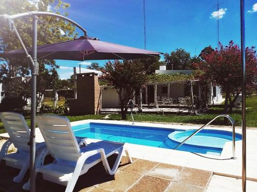 CalabacillasLos Nogales de Yerua的游泳池旁的一对椅子和一把遮阳伞