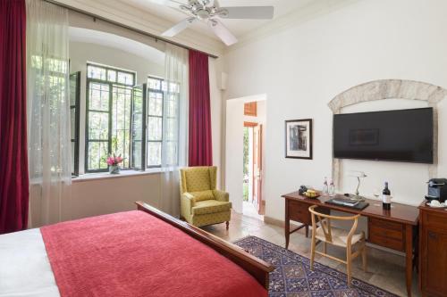 耶路撒冷The American Colony Hotel - Small Luxury Hotels of the World的一间卧室配有一张床、一张书桌和一台电视。