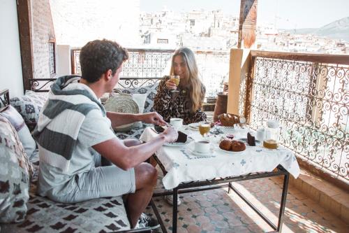 非斯菲斯波利扎比精品旅馆的坐在餐桌旁吃食物的男人和女人