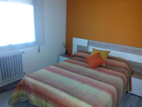 雷阿尔城Andrea´s place的一间卧室配有一张带橙色枕头的床