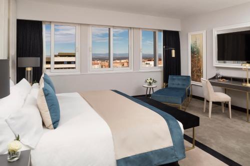马德里卡斯蒂利亚美利亚酒店的卧室配有一张白色大床、一张桌子和椅子