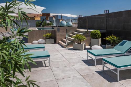 格拉纳达格拉纳达加泰罗尼亚酒店的庭院里设有蓝色的桌子和盆栽植物