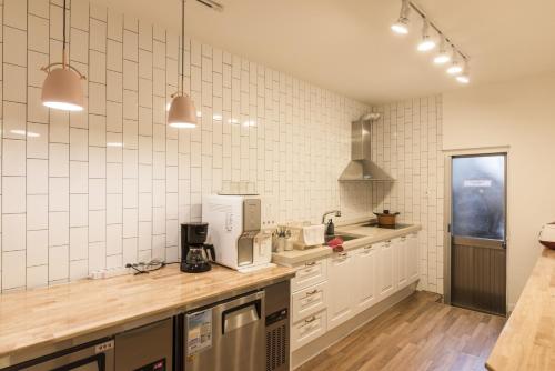 济州市Hannahstay Women Only Guesthouse的厨房设有白色瓷砖墙壁和木制台面