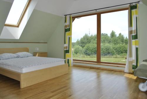 斯米尔泰内Vilks un Briedis Holiday Home & Wellness Area的一间卧室设有一张床和一个大窗户