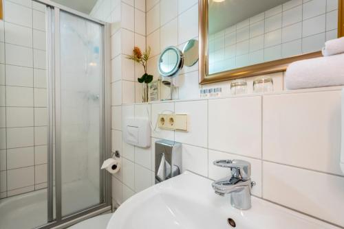 柏林柏林格律瑙大使酒店的一间带水槽、淋浴和镜子的浴室