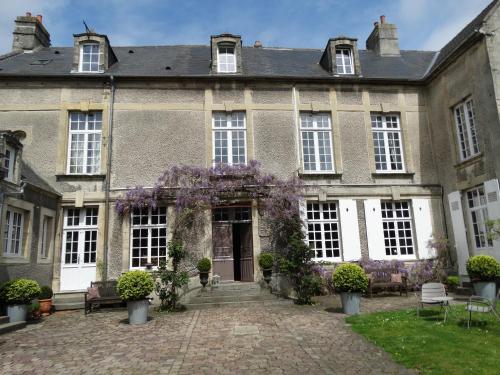 贝叶Hôtel particulier "le clos de la croix"的庭院里一座紫色花圈的古老房子