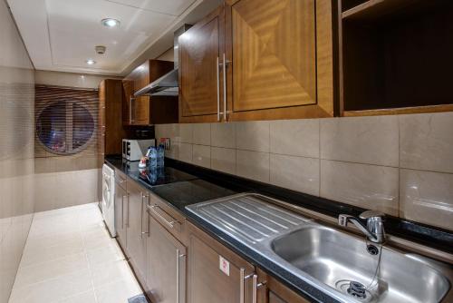 迪拜J5里马尔公寓式酒店的厨房配有不锈钢盥洗盆和木柜