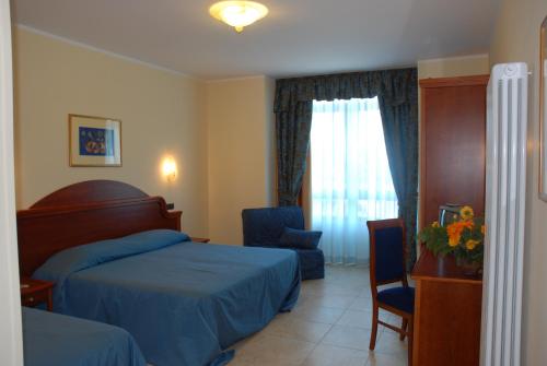 塞拉圣布鲁诺卡拉布里亚公爵酒店的一间卧室设有两张床、一把椅子和一个窗户。