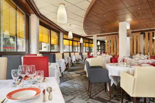 卢尔德罗西酒店的一间设有白色桌子和红色椅子的餐厅