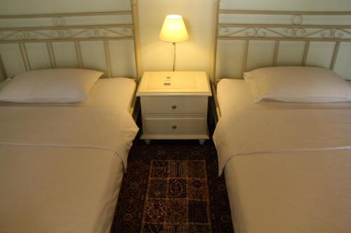 雅加达托芒住宿加早餐旅馆的两张床位于一间房间,中间设有床头柜