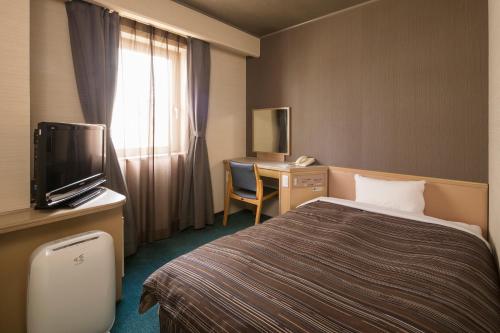 冈山Ark Hotel Okayama -ROUTE INN HOTELS-的酒店客房配有一张床和一张书桌及一台电视
