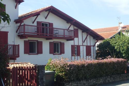 西布勒Chambres d'hôtes GELA ITSASOA Baie的白色的房子,设有红色的阳台和围栏