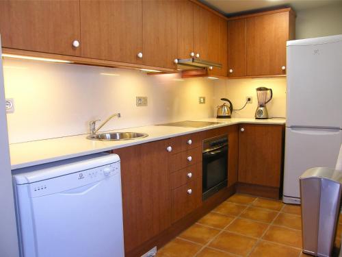安波拉Lirio的厨房配有木制橱柜、水槽和冰箱。