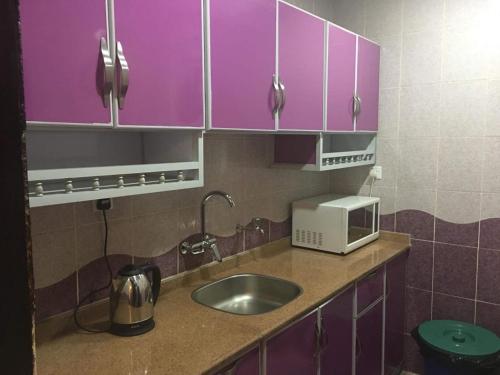 图赖夫Orchida Turaif Hotel 1的厨房配有紫色橱柜、水槽和微波炉