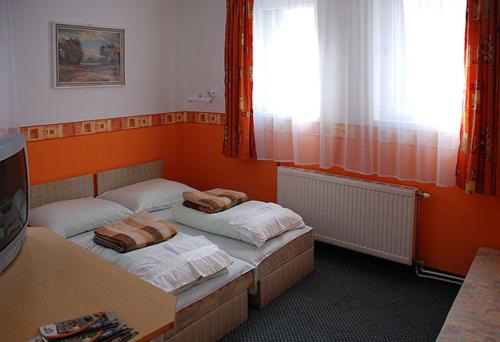 欧罗什哈佐Hotel Flóra**的橙色墙壁客房的两张床