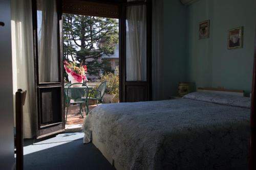 代森扎诺-德尔加达普里马维拉酒店的一间卧室设有一张床,并设有一个通往庭院的开放式门。