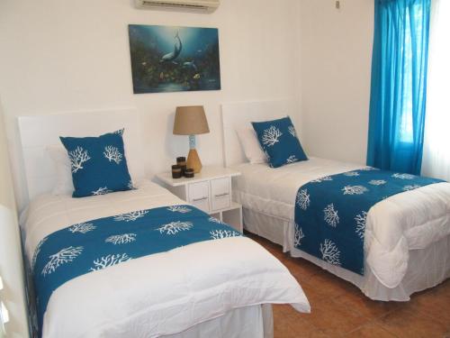 科克Coco Beach Home的配有两张蓝色和白色床单的床铺