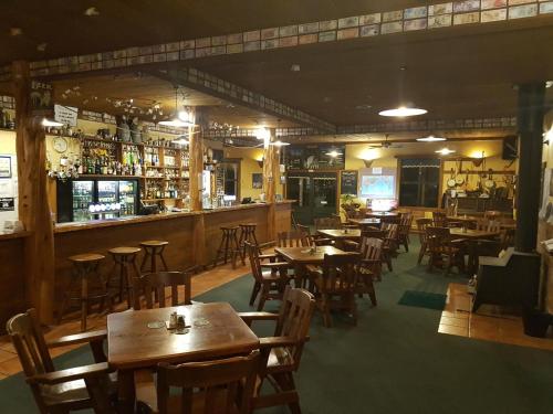 普纳凯基Punakaiki Rocks Hotel & Garden Bar的一间带木桌椅的餐厅和一间酒吧