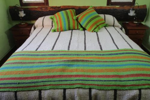 塔菲德尔瓦勒Villa Rural San Miguel de la Loma的一张带彩色条纹毯子和两个枕头的床