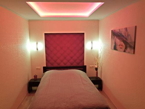 切尔尼戈夫ApartLux 2的一间卧室配有一张带红色床头板和灯的床。