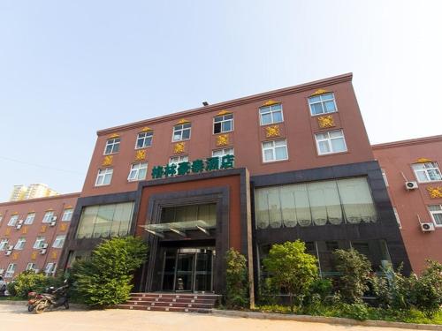 郑州格林豪泰河南省郑州市城南路伯爵商务酒店的一座带窗户和植物的大型砖砌建筑