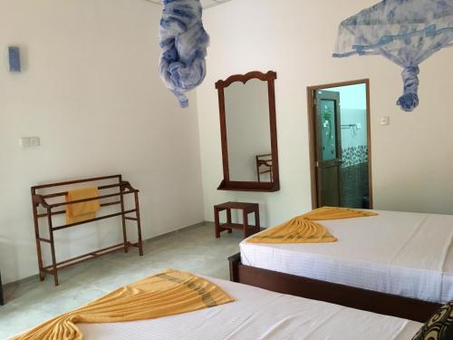 锡吉里亚Sigiri Rangana Guesthouse的带两张床和镜子的客房