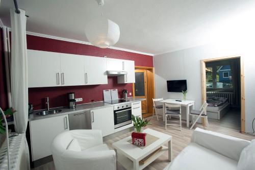 阿伦斯霍普Ferienwohnung Meerzeit的一间厨房和客厅,配有白色家具和红色的墙壁