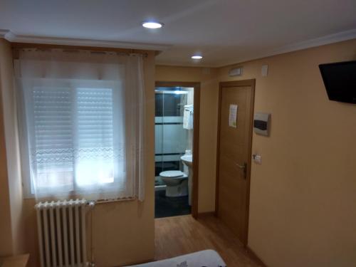 奥伦塞Hostal Lido的一间带卫生间的浴室和一个带散热器的窗户