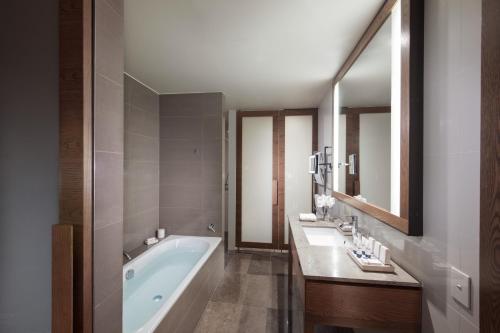 墨尔本墨尔本泛太平洋酒店的带浴缸、两个盥洗盆和镜子的浴室