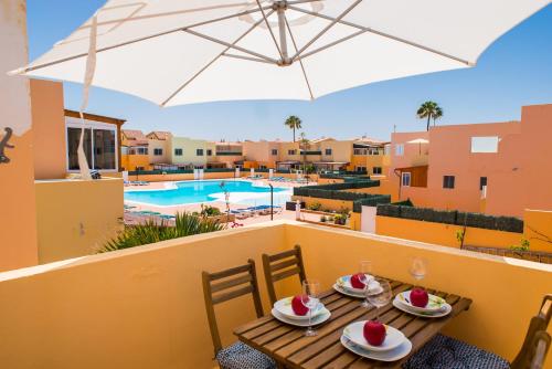 科拉雷侯Apartment Delfines Sand Corralejo By Holidays Home的阳台配有带食物和雨伞的桌子。