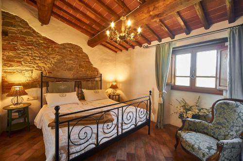 蒙特瓦尔基Ventena Vecchia antico frantoio的一间卧室配有一张床、一把椅子和一个吊灯。