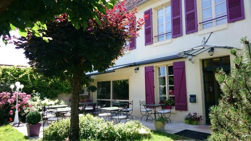 圣夫洛朗坦LOGIS - Hôtel Restaurant Les Tilleuls的紫色百叶窗和庭院的房子