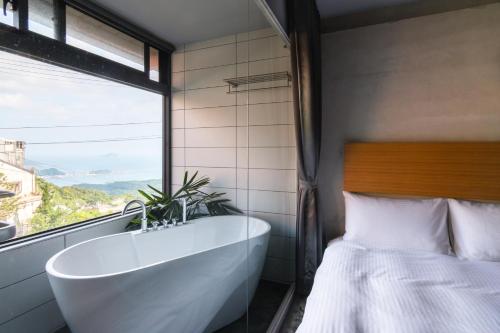 九份H&九份山经海景民宿的带浴缸、床和窗户的浴室