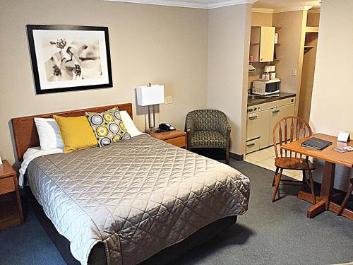 哈利法克斯达特茅斯海岸酒店的一间卧室配有一张床铺和一张桌子,还设有一间厨房