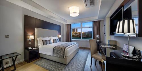 阿布贾阿布贾辉盛阁国际公寓的一间卧室配有一张床、一张书桌和一个窗户。