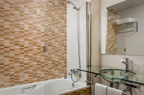 拉塞尔瓦德尔坎普Crisol La Selva的一间带玻璃水槽和浴缸的浴室