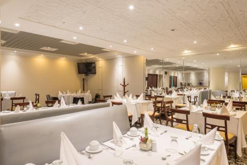 波哥大丹恩AV.19酒店的餐厅配有白色的桌椅和镜子