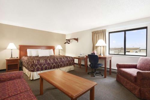 威利斯顿Super 8 by Wyndham Williston ND的酒店客房配有一张床、一张书桌和一张沙发。