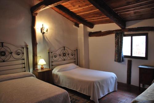 特鲁埃尔丰达托萨尔旅馆的一间卧室设有两张床和窗户。