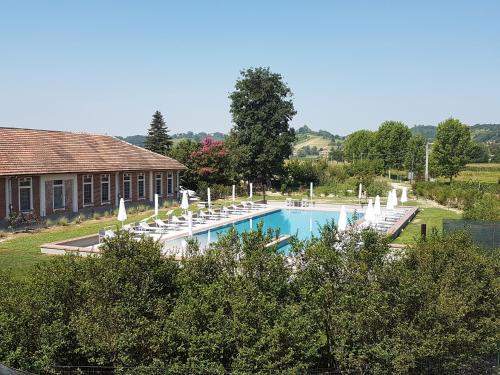 阿斯蒂Locanda Ferro UNO, Golf Città di Asti的一个带白色椅子的游泳池以及一座房子