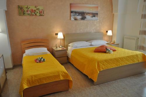 塔兰托7 Contrade的配有黄色床单的酒店客房的两张床