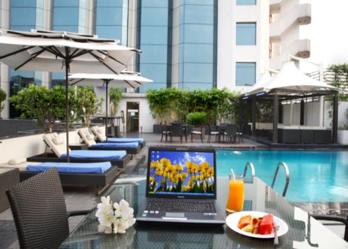 海得拉巴高康达酒店的坐在游泳池旁玻璃桌旁的笔记本电脑